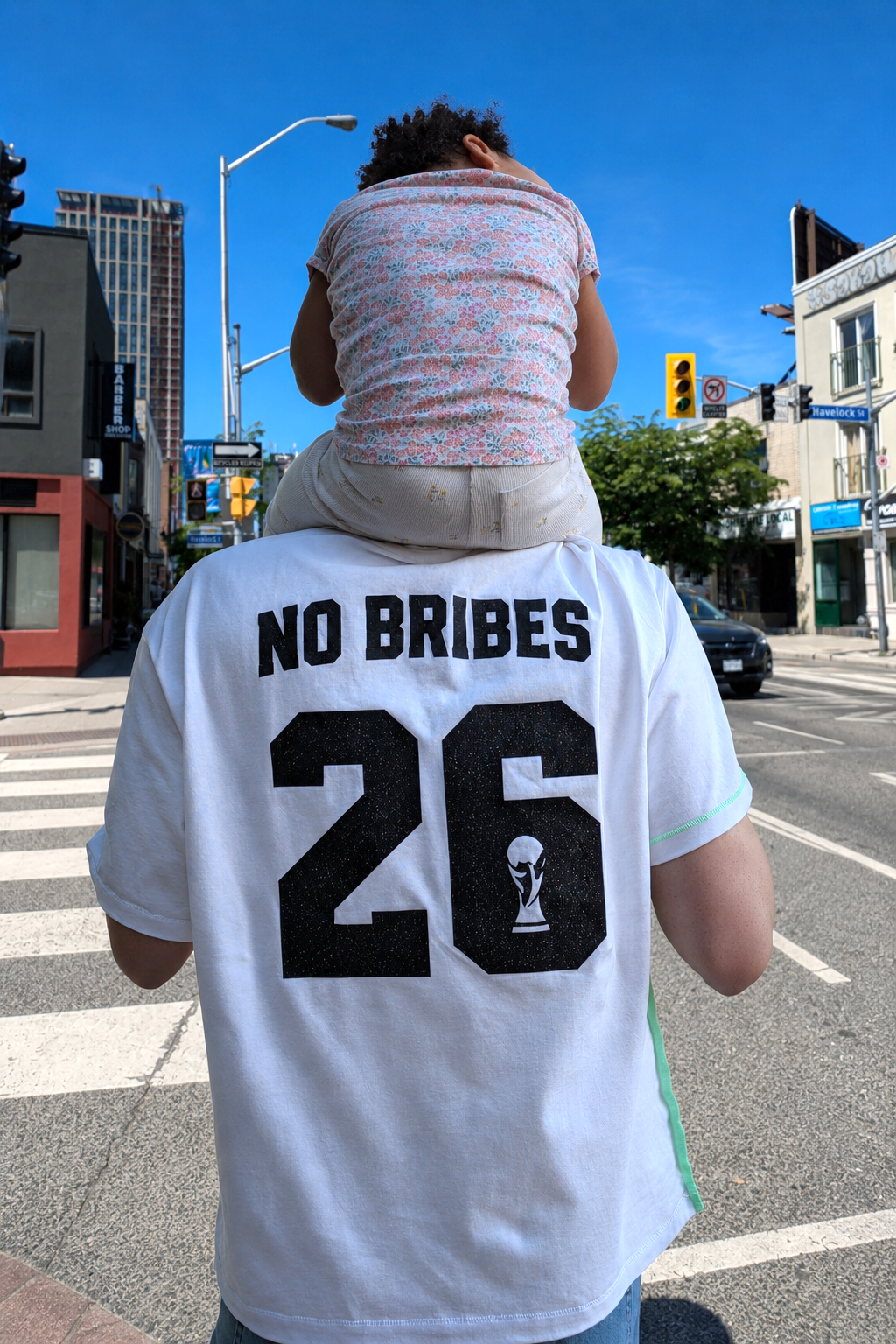 Person wearing a white jersey with 'NO Bribes' and number 26 on a city street.